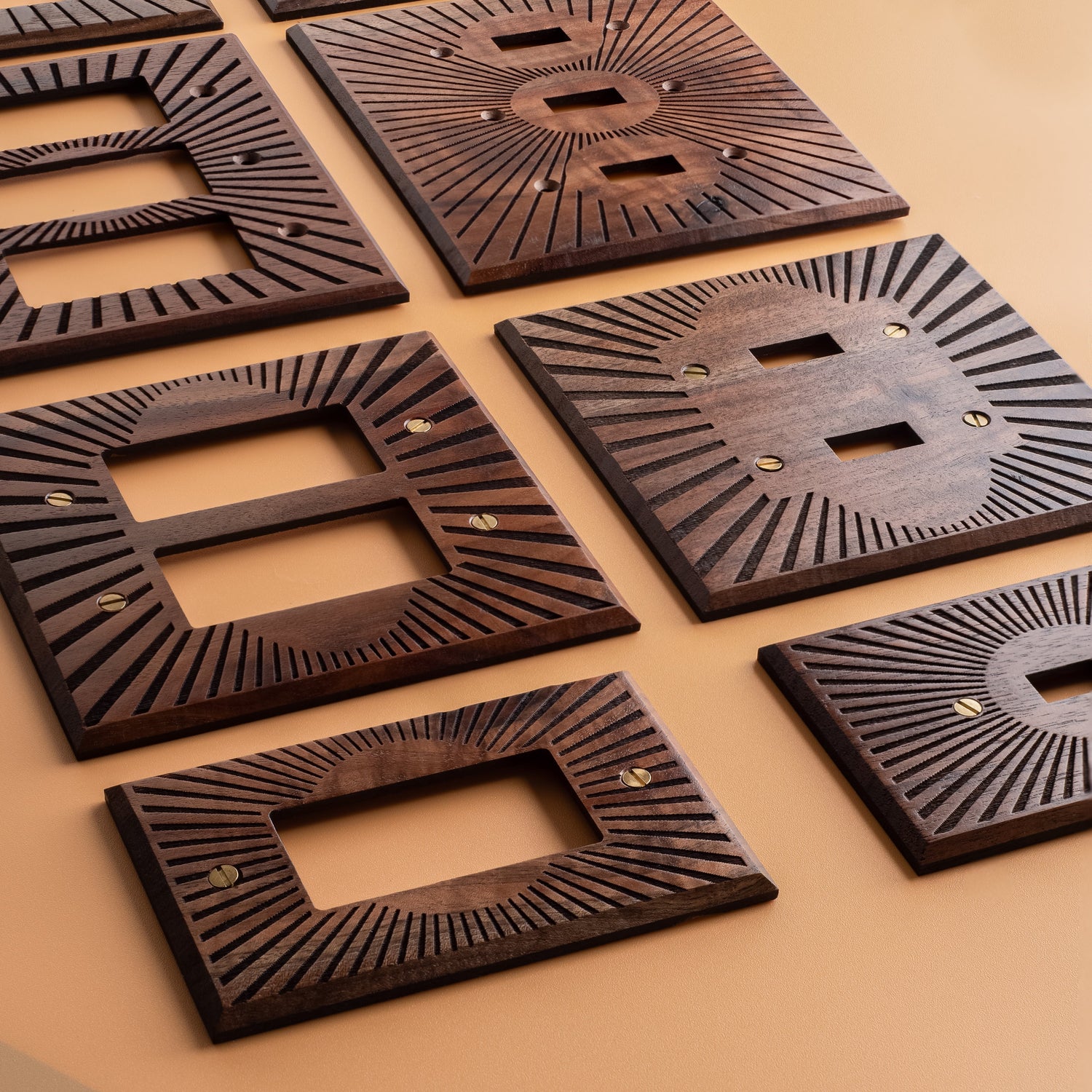 Sunburst Engraved Walnut Light Switch Covers on Orange Citron colored background. Main colors are dark brown and black 
